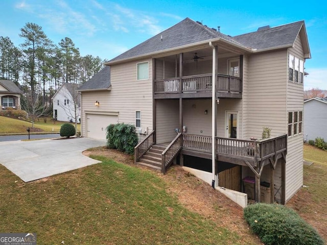 rear view of property featuring ceiling fan, a garage, a yard, and a wooden deck