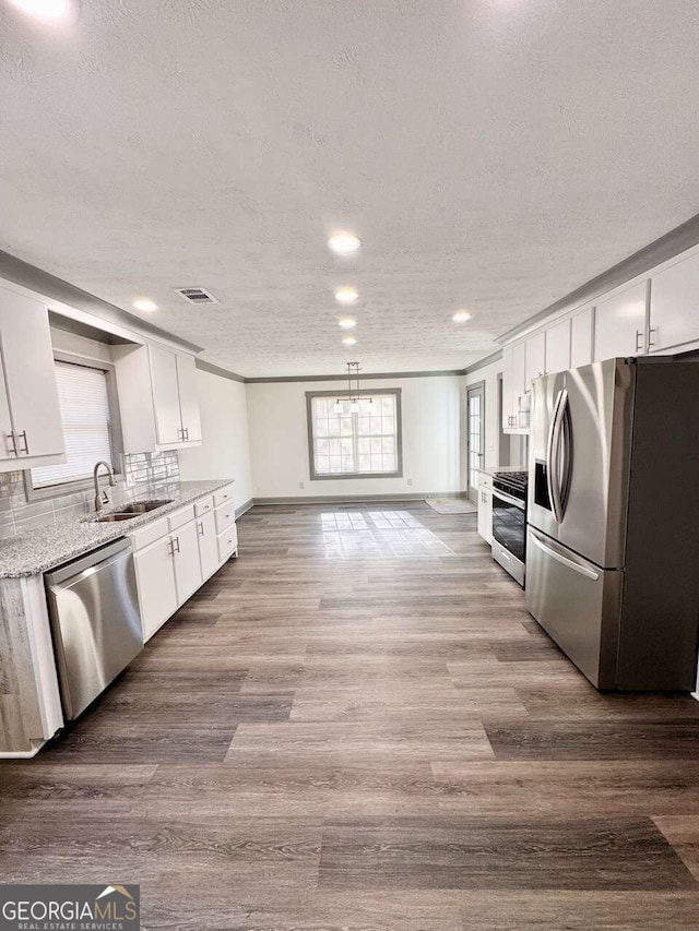 kitchen featuring light stone counters, hardwood / wood-style floors, white cabinets, and stainless steel appliances