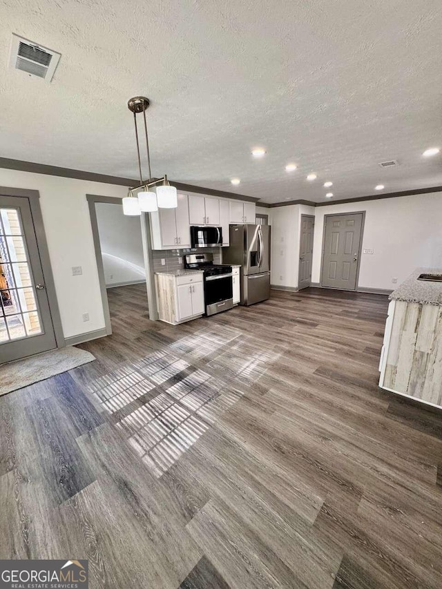 kitchen with appliances with stainless steel finishes, dark hardwood / wood-style flooring, white cabinetry, and hanging light fixtures