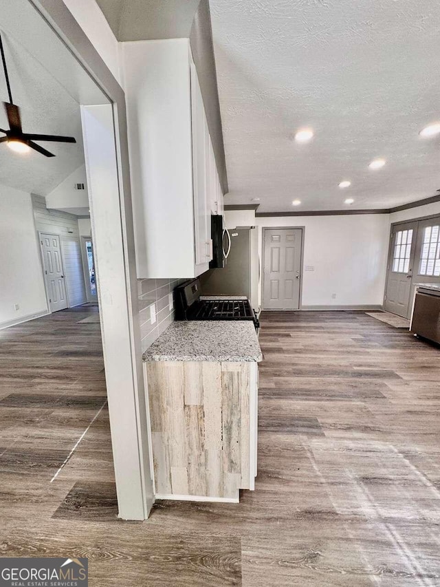 kitchen featuring white cabinetry, black range with gas cooktop, light stone counters, and light wood-type flooring