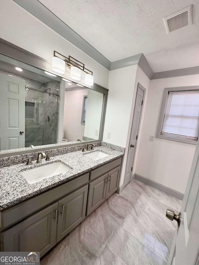 bathroom featuring a textured ceiling, vanity, an enclosed shower, and toilet