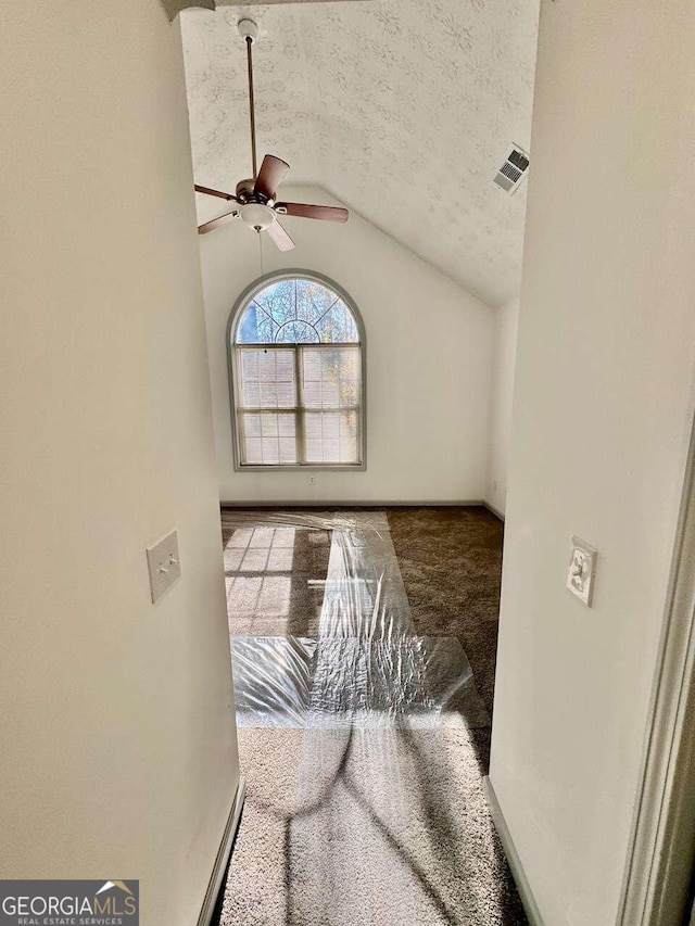 interior space featuring a textured ceiling, ceiling fan, and vaulted ceiling