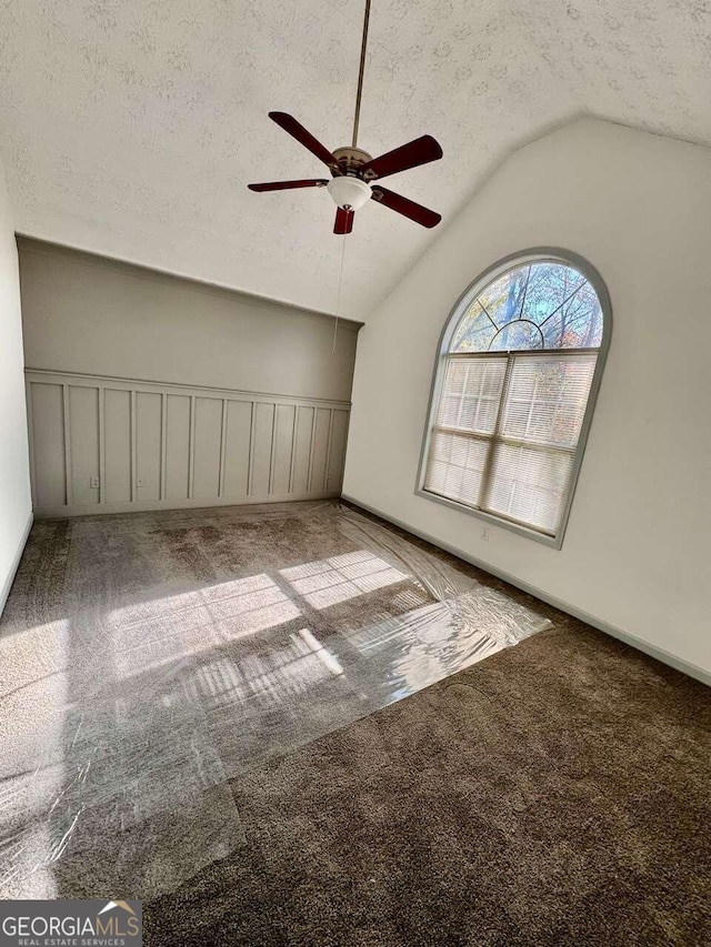 carpeted spare room with a textured ceiling, ceiling fan, and lofted ceiling