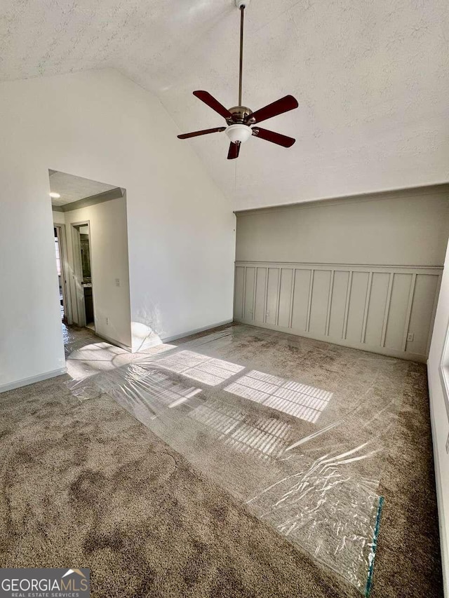 unfurnished room featuring a textured ceiling, ceiling fan, light colored carpet, and vaulted ceiling