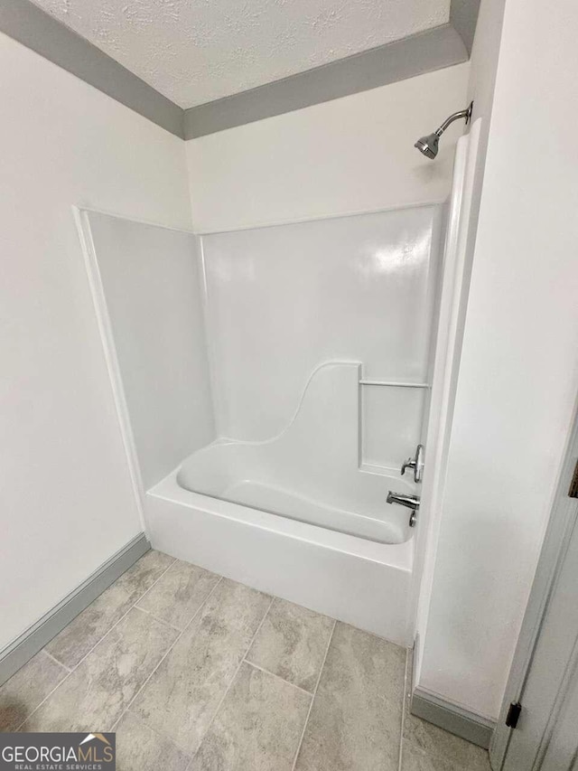 bathroom with shower / bath combination and a textured ceiling