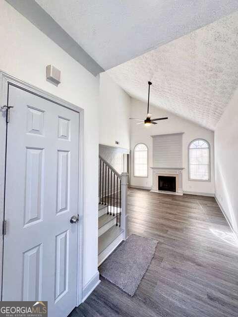 interior space with ceiling fan, dark hardwood / wood-style flooring, a textured ceiling, and vaulted ceiling