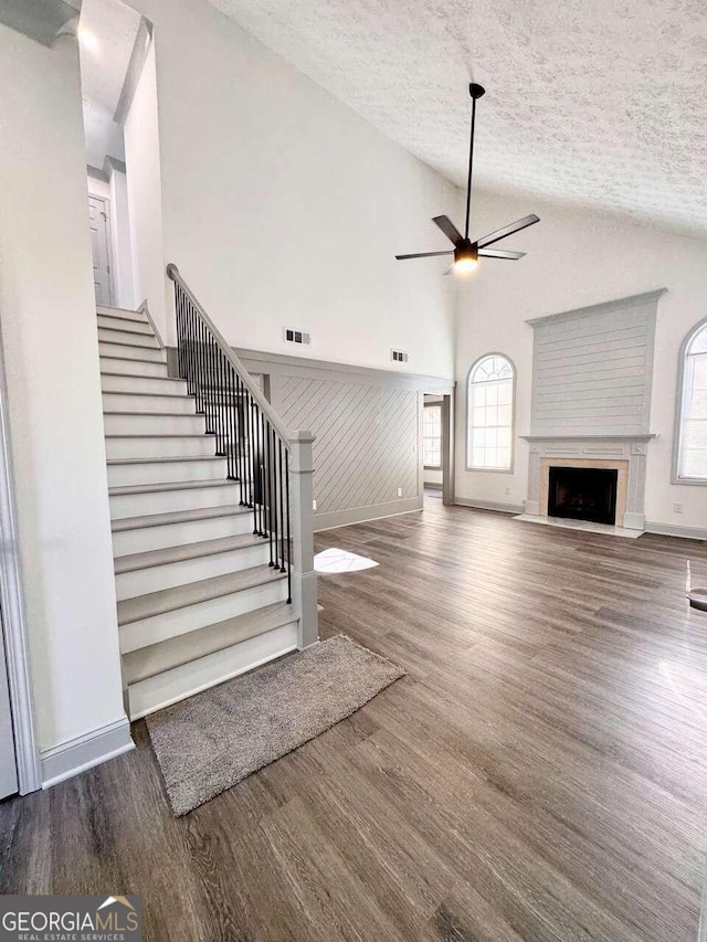 unfurnished living room featuring a textured ceiling, dark wood-type flooring, and a healthy amount of sunlight