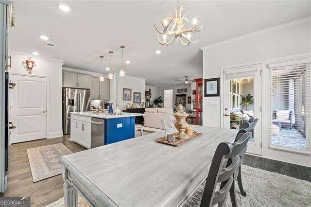 dining room featuring wood-type flooring, ceiling fan with notable chandelier, and ornamental molding