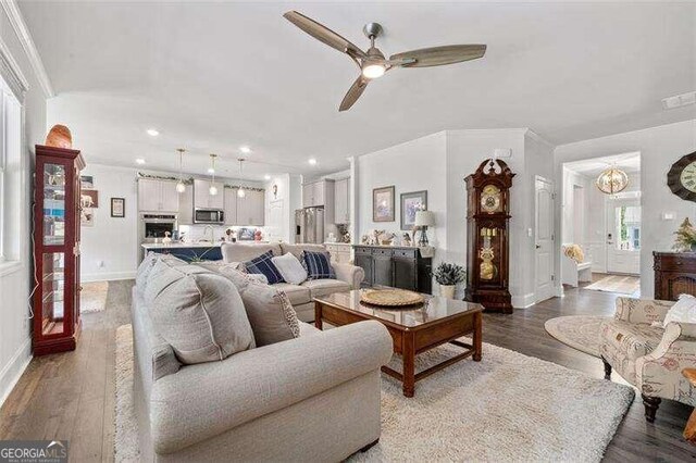 living room with ceiling fan with notable chandelier, hardwood / wood-style flooring, and crown molding