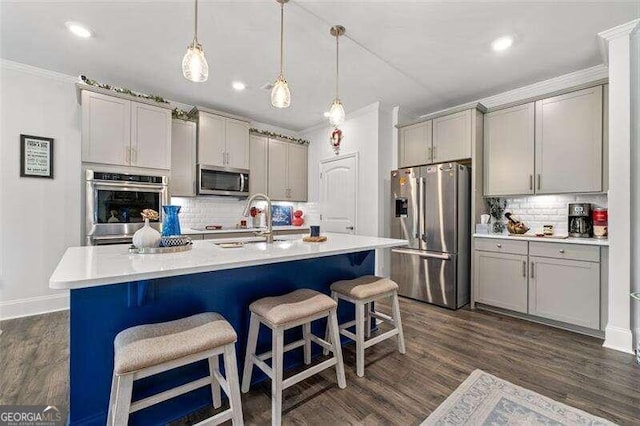 kitchen featuring appliances with stainless steel finishes, dark hardwood / wood-style flooring, gray cabinets, and pendant lighting