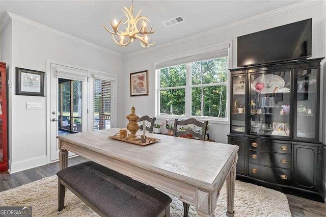 dining space featuring dark wood-type flooring, a notable chandelier, and ornamental molding