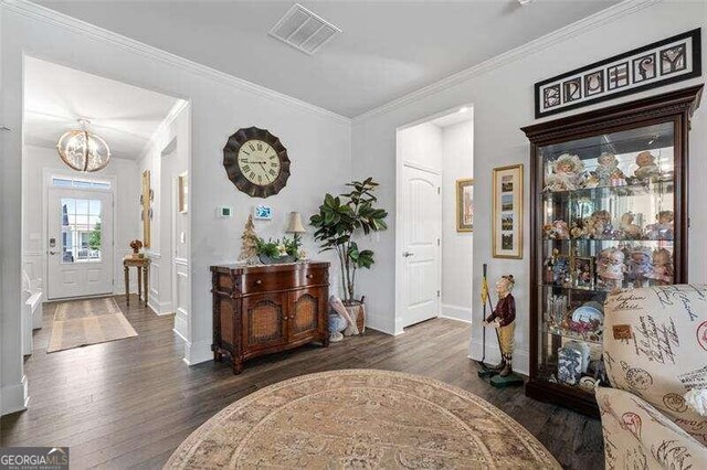 foyer featuring dark hardwood / wood-style flooring, ornamental molding, and an inviting chandelier