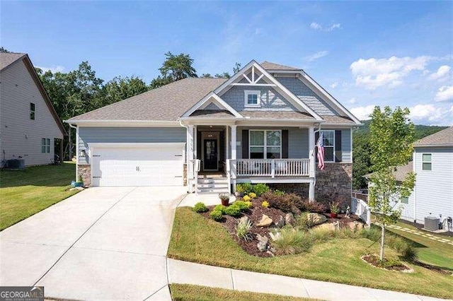 craftsman-style house with a porch, a garage, central air condition unit, and a front yard