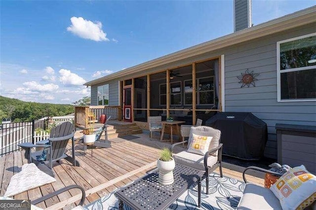 wooden terrace featuring a sunroom and a grill