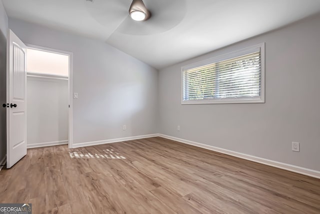 unfurnished bedroom with ceiling fan, light hardwood / wood-style floors, a closet, and vaulted ceiling