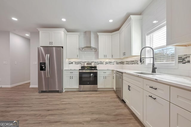 kitchen featuring sink, wall chimney exhaust hood, stainless steel appliances, and light wood-type flooring