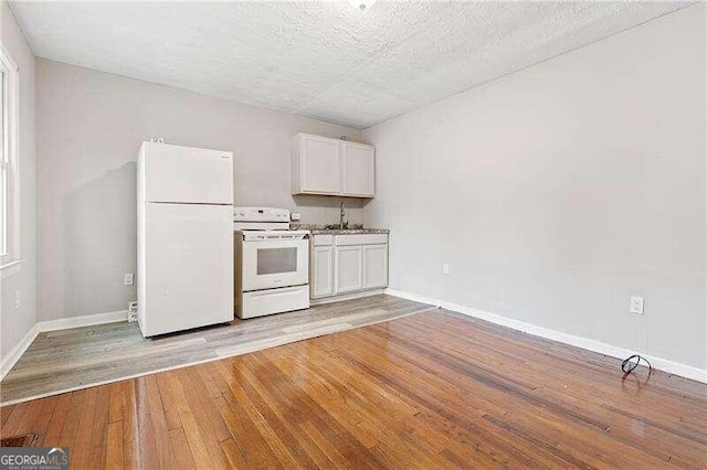 kitchen featuring white cabinetry, sink, white appliances, and light wood-type flooring