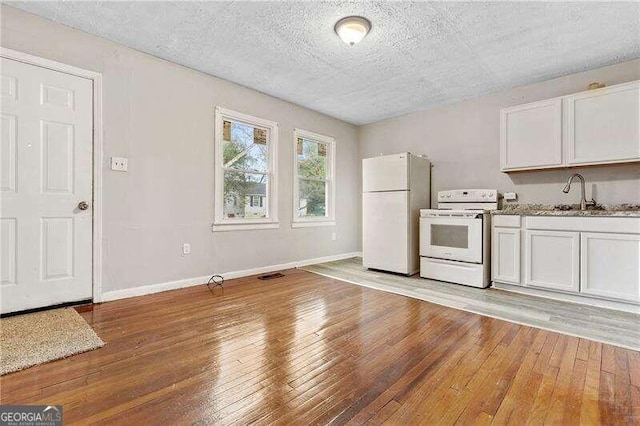 kitchen with sink, light hardwood / wood-style floors, a textured ceiling, white appliances, and white cabinets