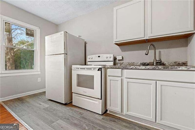 kitchen featuring sink, light hardwood / wood-style floors, a textured ceiling, white appliances, and white cabinets