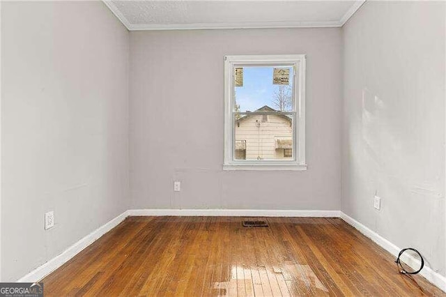 empty room with hardwood / wood-style floors and ornamental molding