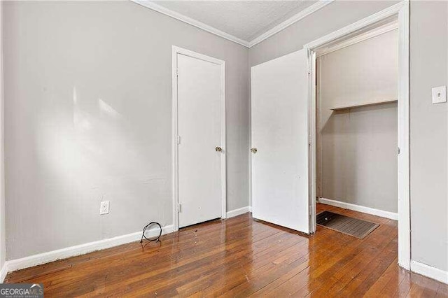 unfurnished bedroom featuring a closet, dark wood-type flooring, and ornamental molding