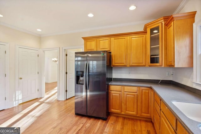 kitchen with stainless steel refrigerator with ice dispenser, light hardwood / wood-style flooring, crown molding, and sink