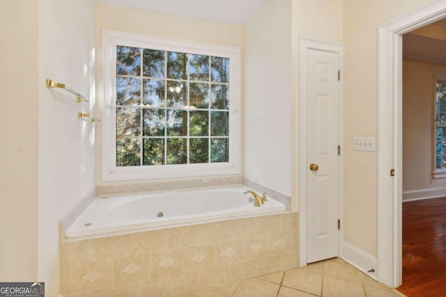 bathroom with hardwood / wood-style flooring, plenty of natural light, and tiled tub