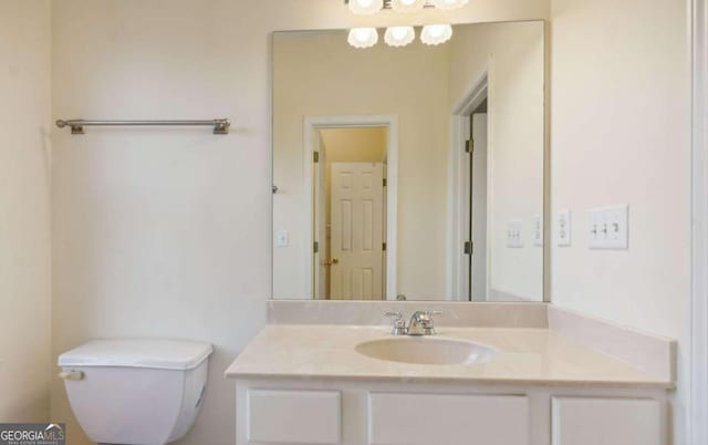 bathroom featuring vanity, an inviting chandelier, and toilet