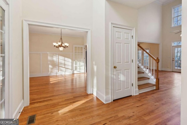 interior space with a towering ceiling, hardwood / wood-style flooring, crown molding, and a notable chandelier