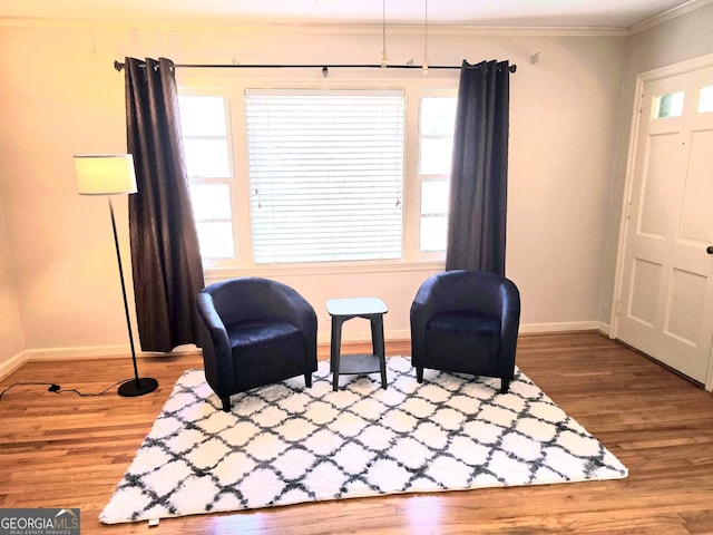 living area with crown molding and wood-type flooring