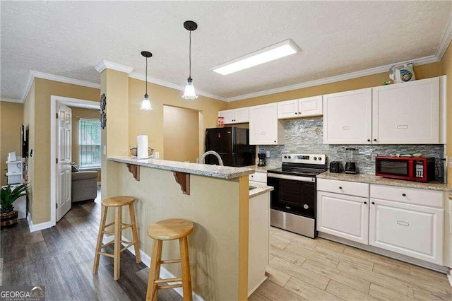 kitchen with ornamental molding, a breakfast bar, black appliances, light hardwood / wood-style flooring, and white cabinetry