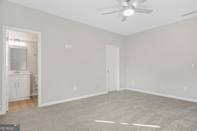 unfurnished bedroom featuring connected bathroom, light colored carpet, ceiling fan, and sink