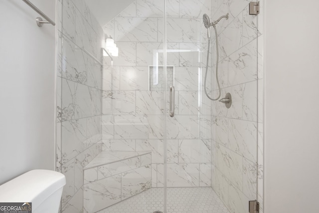 bathroom featuring toilet and a shower with door