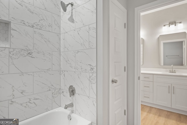 bathroom with tiled shower / bath combo, wood-type flooring, and vanity