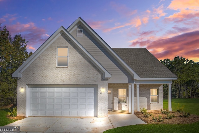 view of front of home featuring a yard, covered porch, and a garage