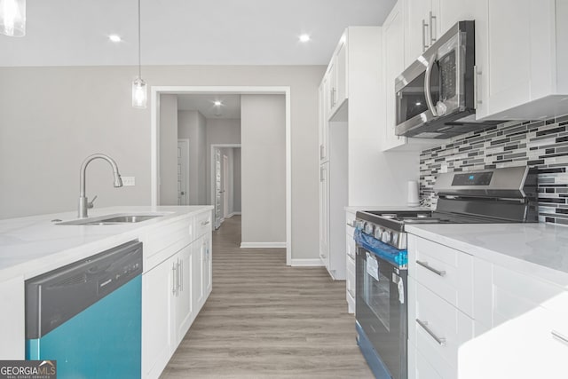 kitchen with white cabinets, sink, hanging light fixtures, light wood-type flooring, and stainless steel appliances