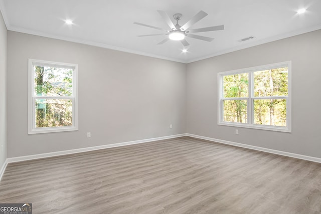 empty room featuring ornamental molding, light hardwood / wood-style floors, ceiling fan, and a healthy amount of sunlight