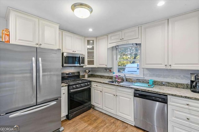 kitchen featuring sink, white cabinetry, stainless steel appliances, and light wood-type flooring