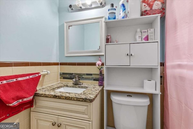 bathroom with vanity, toilet, and tile walls