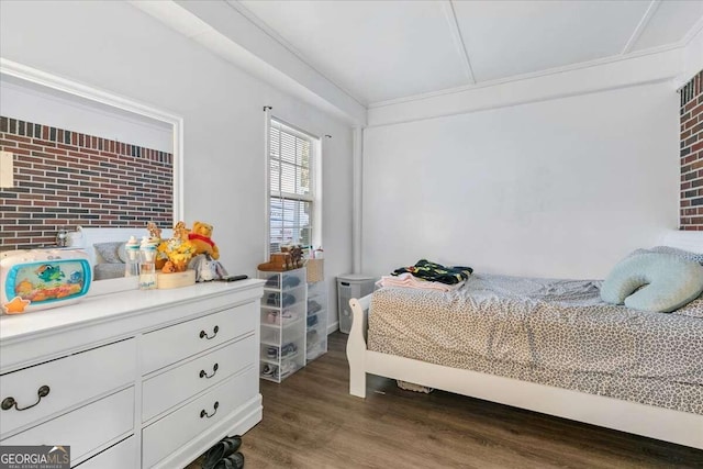 bedroom with dark wood-type flooring and brick wall