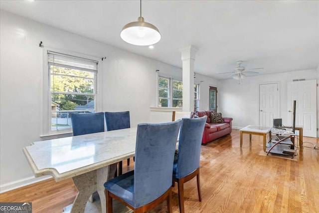 dining space featuring ceiling fan, ornate columns, a wealth of natural light, and light hardwood / wood-style flooring