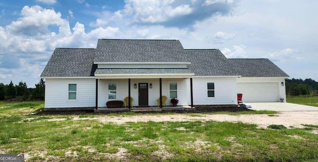 view of front of property with a porch, a garage, and a front lawn