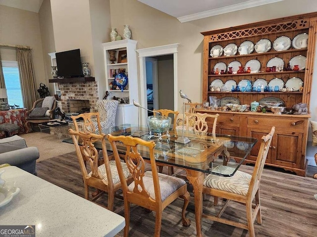 dining room featuring hardwood / wood-style flooring, a brick fireplace, and ornamental molding