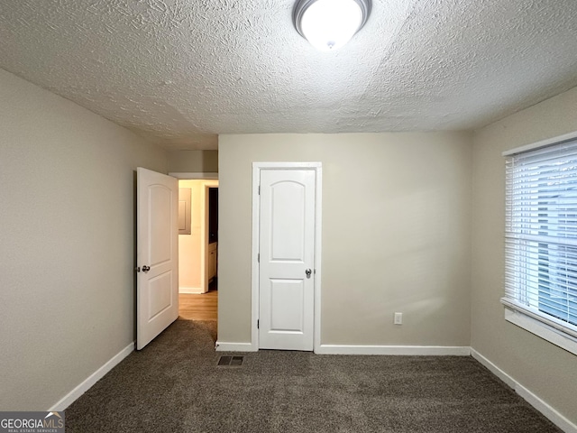 unfurnished bedroom featuring dark colored carpet and a textured ceiling