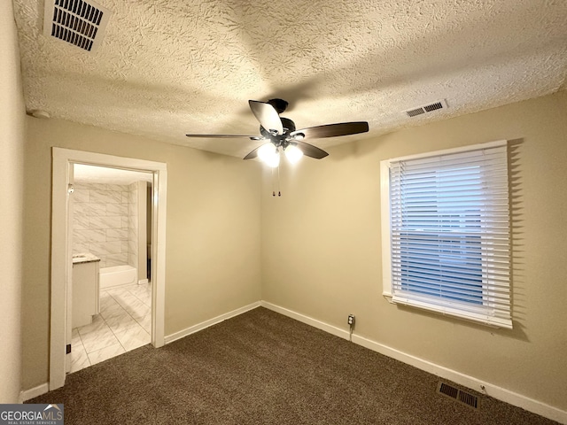 unfurnished bedroom with ceiling fan, light colored carpet, and a textured ceiling