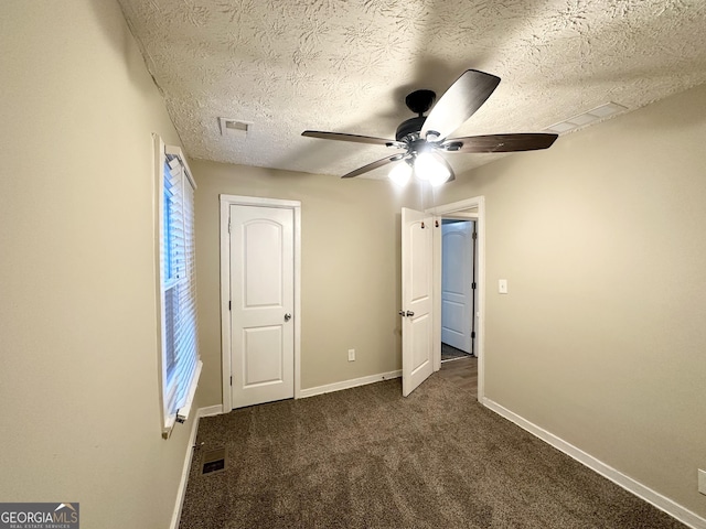 unfurnished bedroom with dark colored carpet, a textured ceiling, and ceiling fan