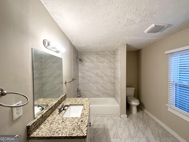 full bathroom featuring vanity, tiled shower / bath combo, a textured ceiling, and toilet