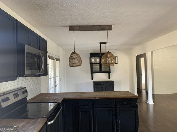 kitchen with dark hardwood / wood-style flooring, stainless steel appliances, butcher block countertops, and hanging light fixtures