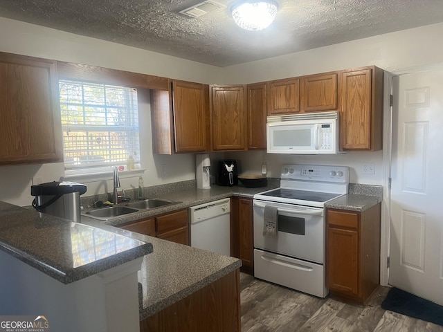 kitchen featuring kitchen peninsula, sink, white appliances, and a textured ceiling