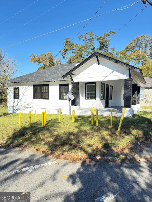 view of front of home with covered porch and a front lawn